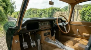 A detailed view of a classic car dashboard featuring a range of toggle switches, Smiths-style analogue dials, and a period-correct radio unit.