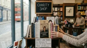 A curated shelf of second-hand celebrity memoirs in a UK charity shop with pricing and donation information.