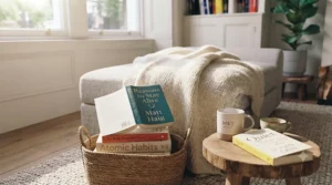A comfortable reading corner with a soft blanket and a stack of top-selling happiness books ready to read.